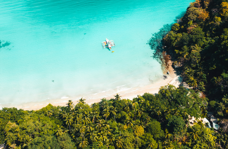 Airplane flying over tropical Philippine islands with turquoise water below